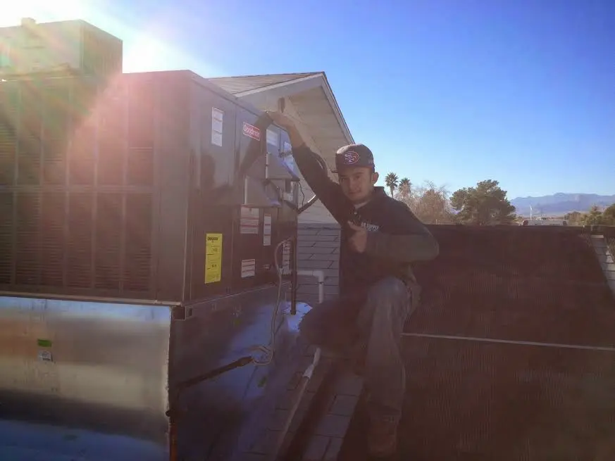 HVAC technician performing AC Tune-Up on a rooftop unit in Warrenville